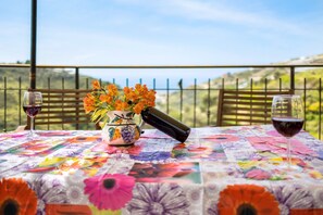 Ein Tisch mit einer blumigen Tischdecke, einer Blumenvase, einem Weinglas und einer Flasche.