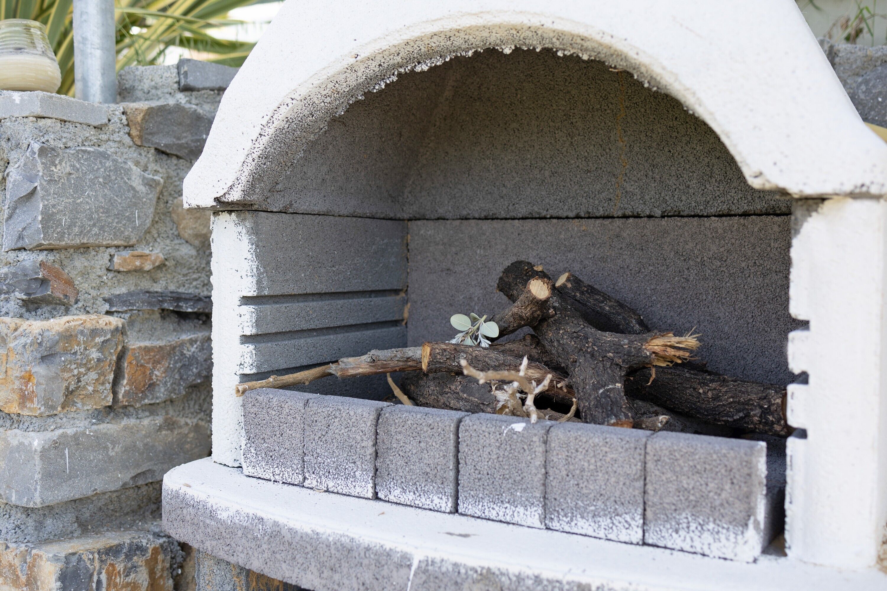 A stone-built outdoor oven with a brick base, surrounded by a stone wall.