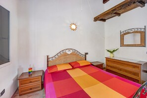 Une chambre à coucher comprenant un lit, une table de chevet en bois, une commode et un miroir fixé au mur.