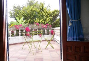 A patio with a green metal chair and a small table, a stone balustrade, and pink flowers. - Villa 'Casa Pera' with Sea View, Pool, Wi-Fi, Garden & Terrace (Jávea)