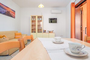 Ein Wohnzimmer mit einer Couch, einem Esstisch und einem Schrank mit Geschirr.
