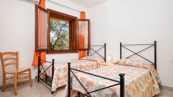 Een kamer met twee bedden, een stoel en een raam met gordijnen.