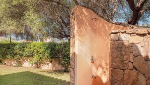 Un mur de pierres avec une porte, une zone herbeuse et des arbres en arrière-plan.