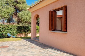 Un edificio con facciata rosa, un patio in pietra e una poltrona blu.