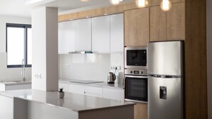 Een moderne keuken met witte kastjes, roestvrijstalen apparatuur en hanglampen.