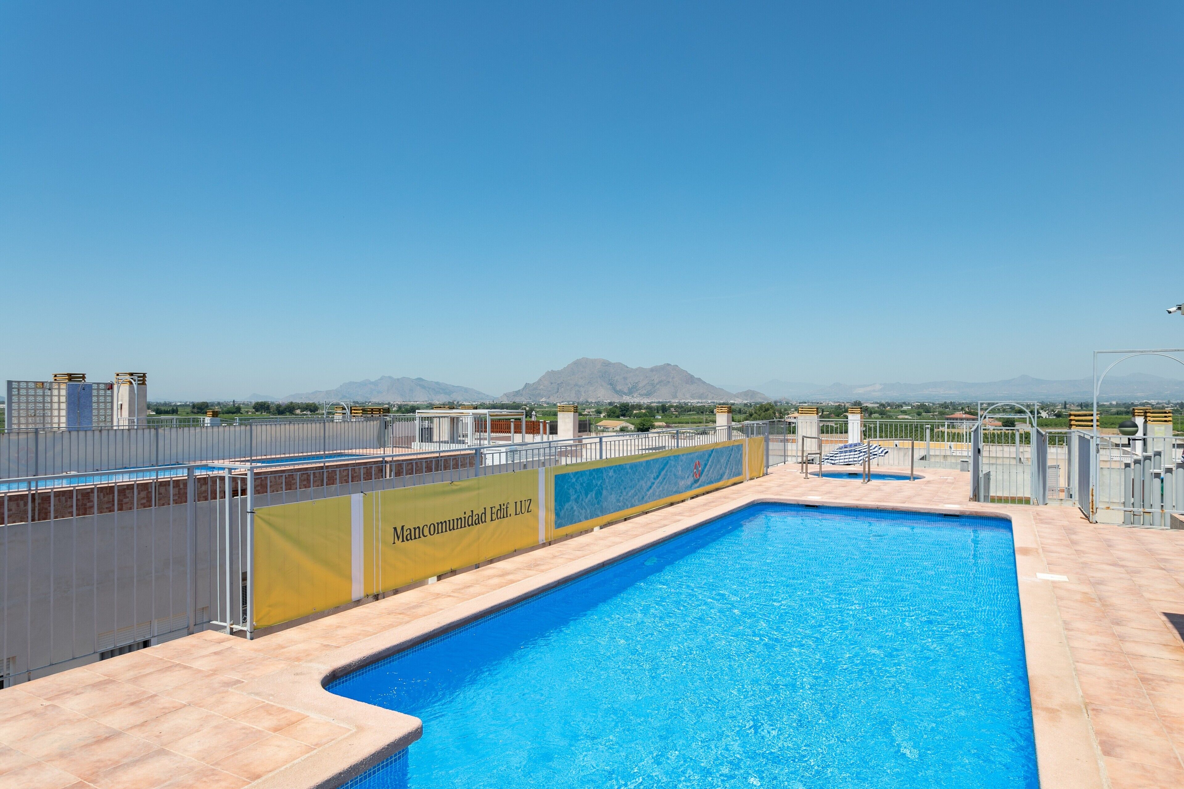Una piscina con vistas a montañas, un área cercada y un cartel con texto.