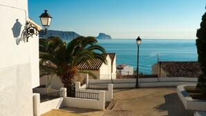 A coastal view with a building, palm trees, and a street lamp. - Apartment 'Luz de Altea' with Sea View, Pool, Wi-Fi, Balcony & Terrace (Altea)
