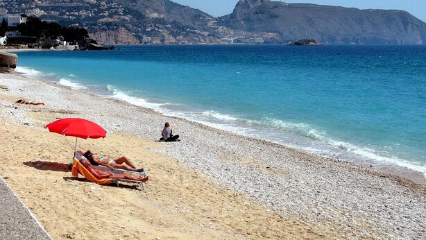 A beach with pebbles, a red umbrella, and a person sunbathing. - Apartment 'Luz de Altea' with Sea View, Pool, Wi-Fi, Balcony & Terrace (Altea)
