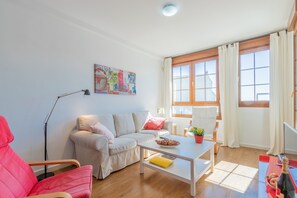 Uma sala de estar com sofá, mesa de centro, abajur e janela com cortinas.