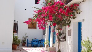 A narrow courtyard with white walls, blue doors, and a table with blue chairs. - Apartment 'Luz de Altea' with Sea View, Pool, Wi-Fi, Balcony & Terrace (Altea)