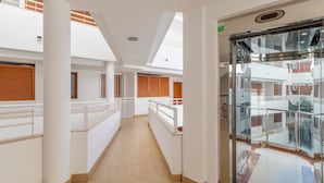 A corridor with white walls, wooden shutters, and a glass elevator. - Apartment 'Luz de Altea' with Sea View, Pool, Wi-Fi, Balcony & Terrace (Altea)