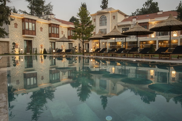Una piscina al aire libre, sombrillas, sillones reclinables de piscina