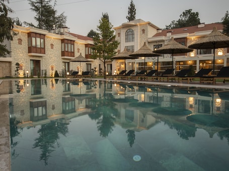 Una piscina al aire libre, sombrillas, sillones reclinables de piscina