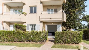 A multi-story residential building with balconies, a gated entrance, and a well-maintained hedge. - Apartment 'Xiprer' with Terrace, Shared Pool & Wi-Fi (PORT POLLENÇA)