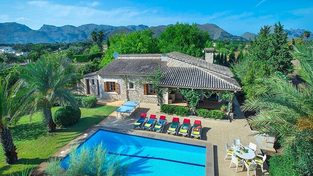 Una villa con piscina, mobiliario exterior y vistas a las montañas.