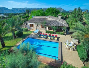 A villa with a swimming pool, outdoor seating, and a view of mountains.