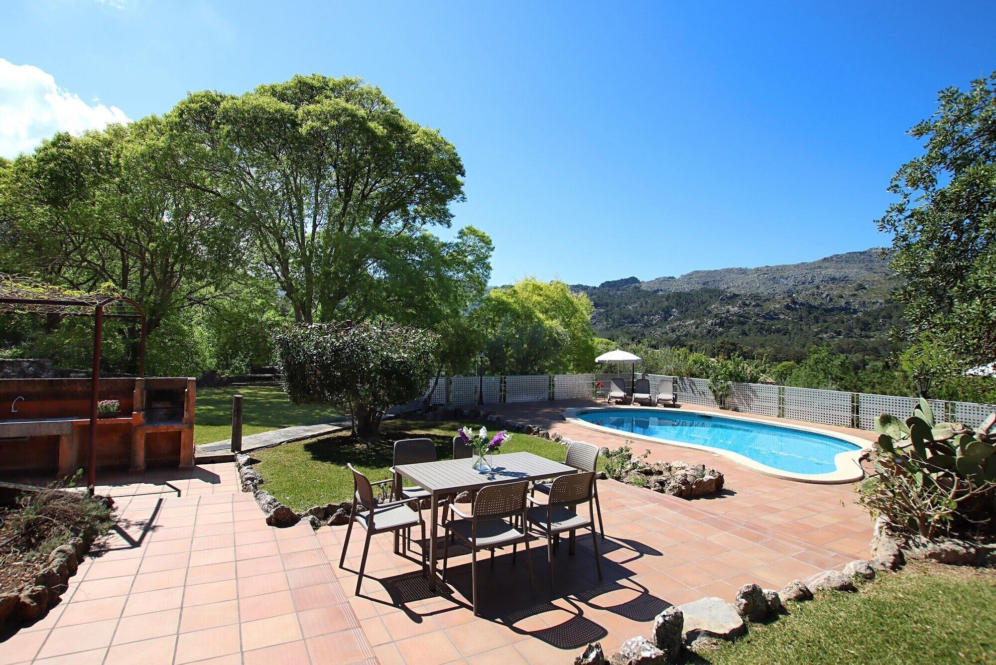 A backyard with a swimming pool, patio furniture, and a view of the mountains.