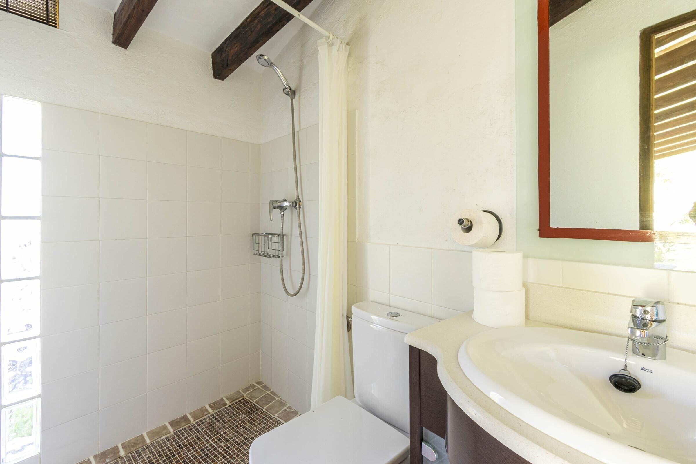 A bathroom with a shower, toilet, sink, and a mirror.