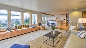 Ein modernes Wohnzimmer mit einer Couch, einem Couchtisch und großen Fenstern mit Blick ins Freie.