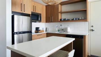 Una cocina moderna con armarios de madera, electrodomésticos de acero inoxidable, encimera blanca y lavavajillas integrado.
