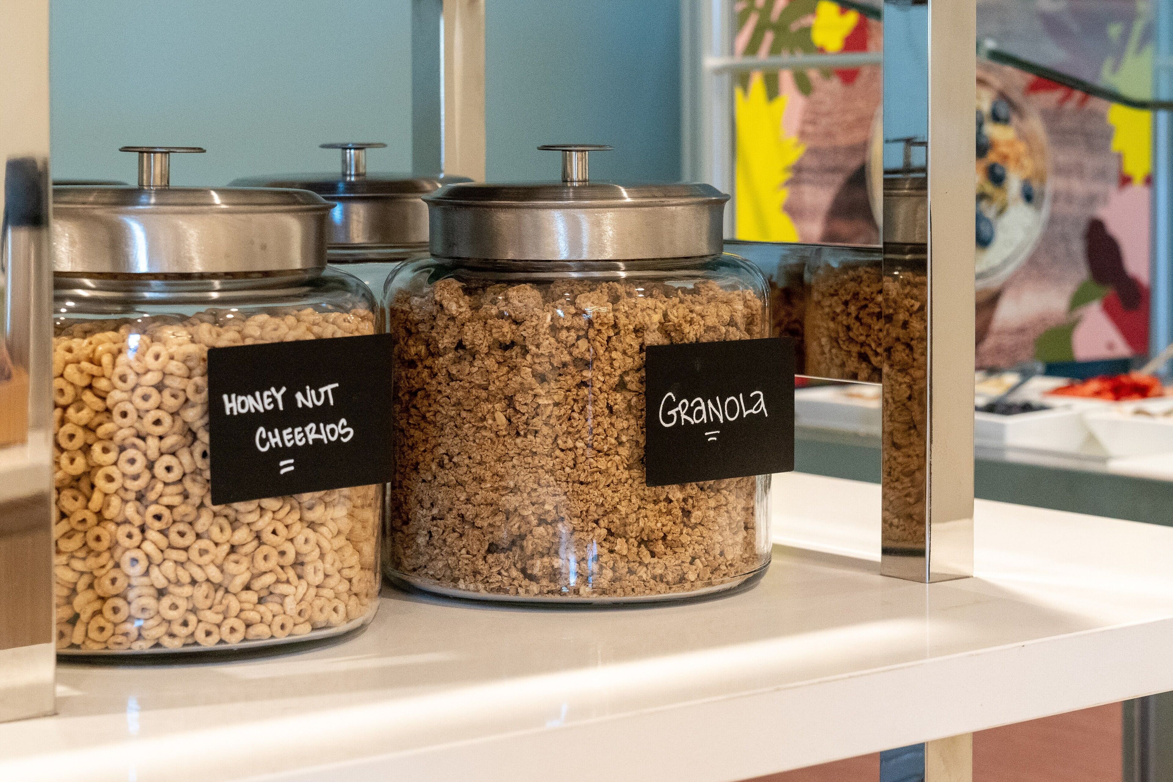 Three glass jars labeled with different cereal types on a white shelf.