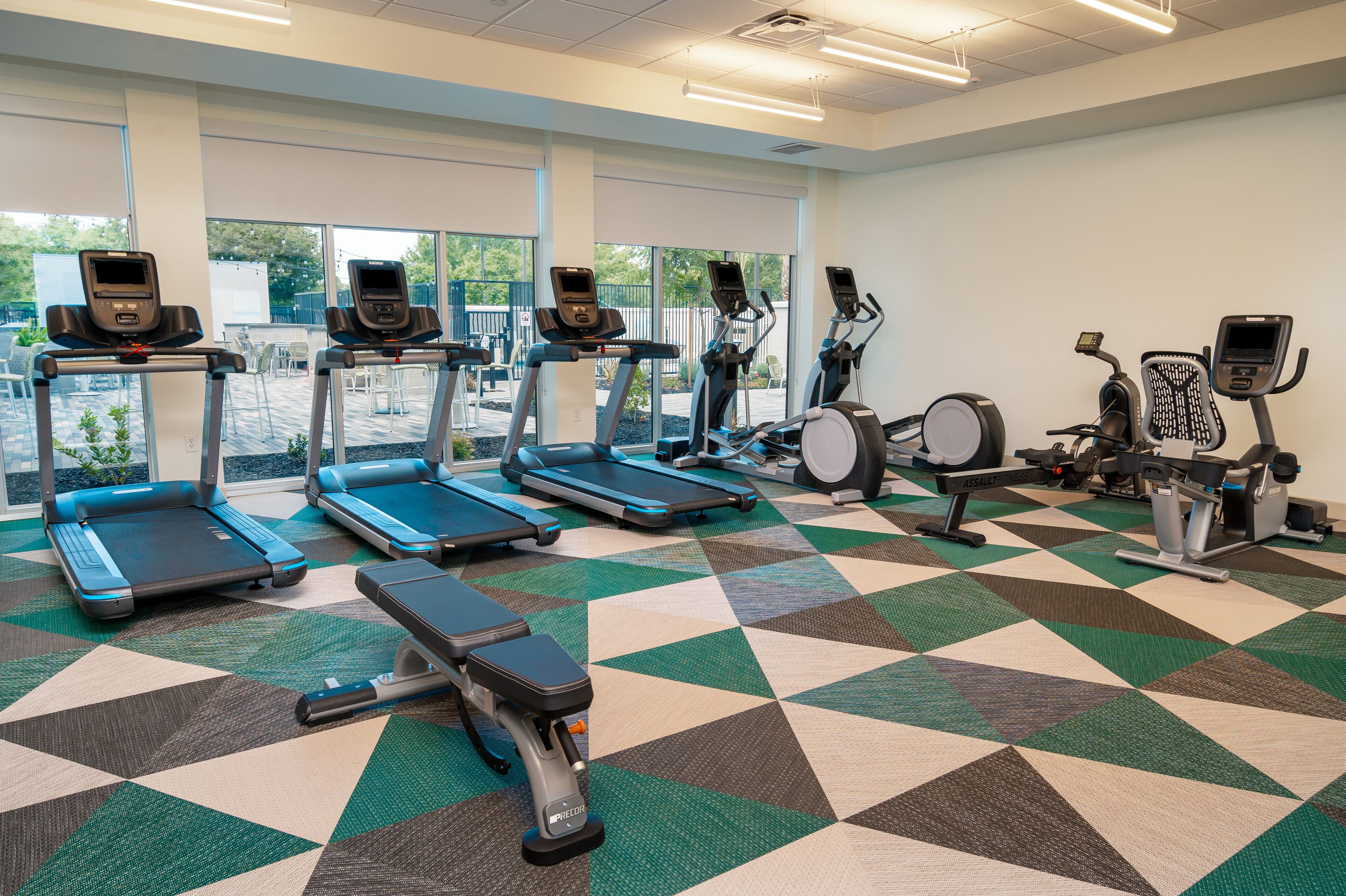 A gym with treadmills, stationary bikes, and a bench.
