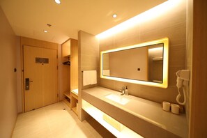 A modern bathroom with a large mirror, a sink, and a telephone. - Ji Hotel (Changchun)