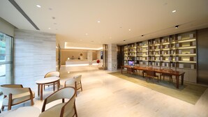 Eine moderne Hotelhalle mit einer Rezeption, einer Sitzecke und einem großen Bücherregal.