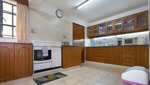 Una cocina con armarios de madera, estufa, microondas y un cubo de basura.
