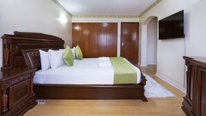 Un dormitorio con una cama de madera, un aparador, un televisor y un armario.