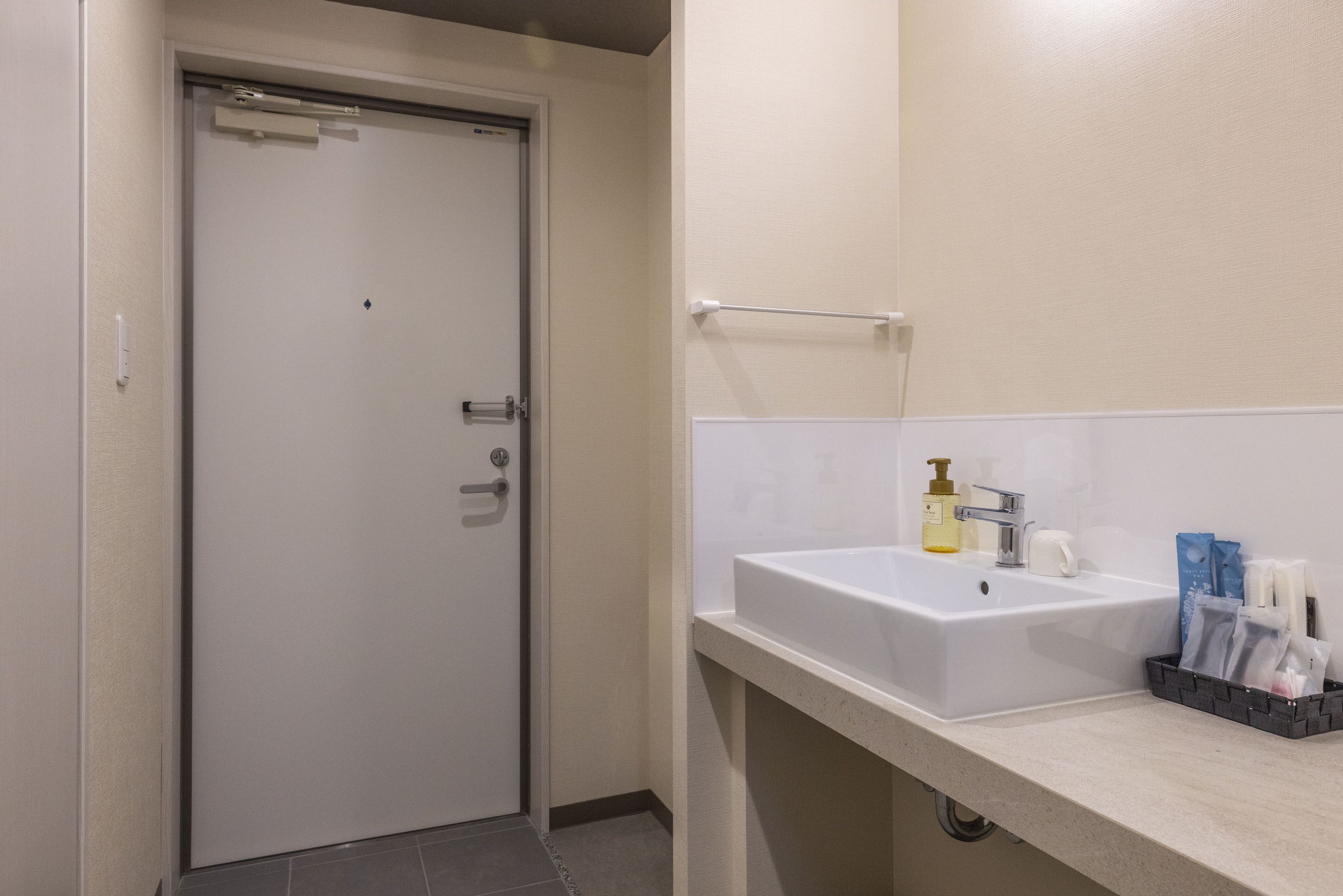 A bathroom with a white sink, a towel rack, and toiletries on the counter.