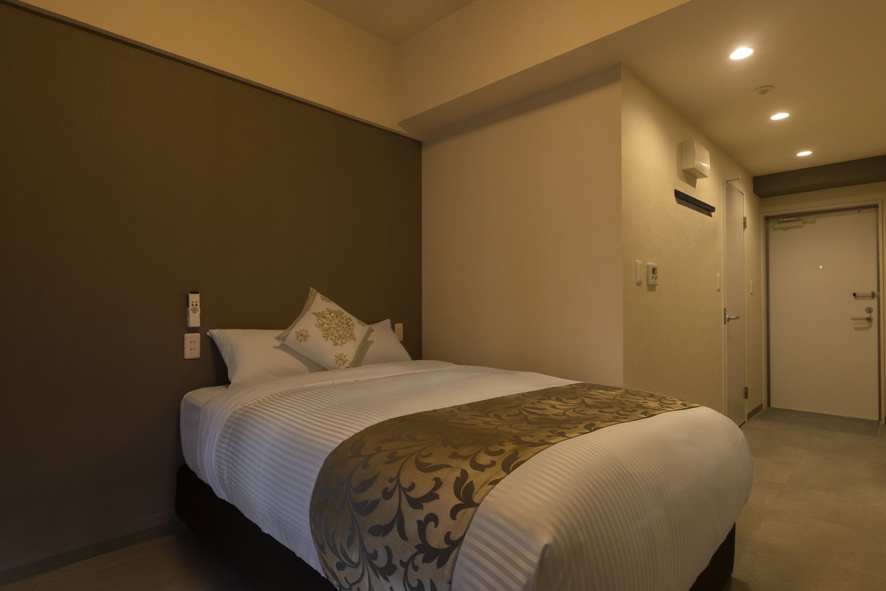 A hotel room with a large bed, a bedside table, a wardrobe, and a door.