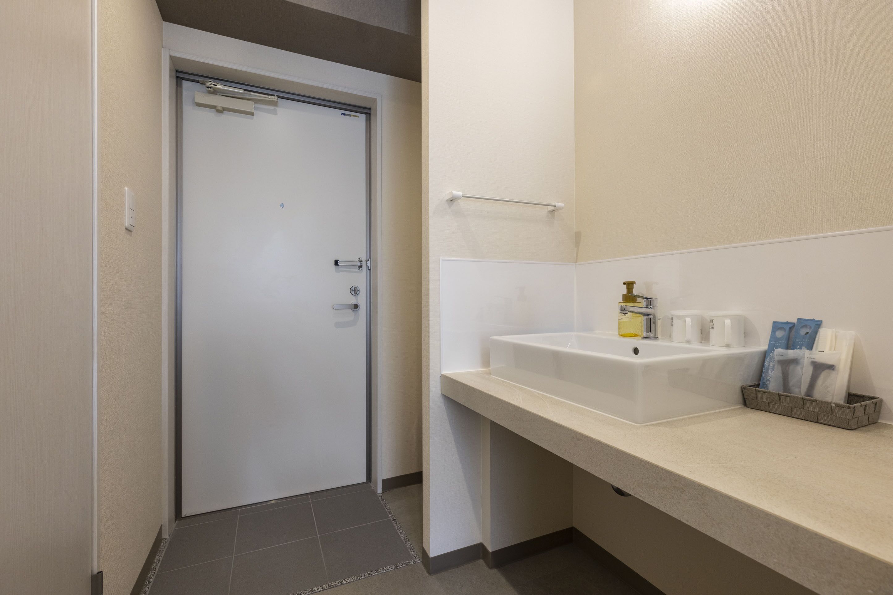 A modern bathroom with a white sink, a towel rack, and toiletries on the counter.