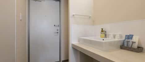Un baño moderno con un lavamanos blanco, un perchero y artículos de aseo en la encimera.