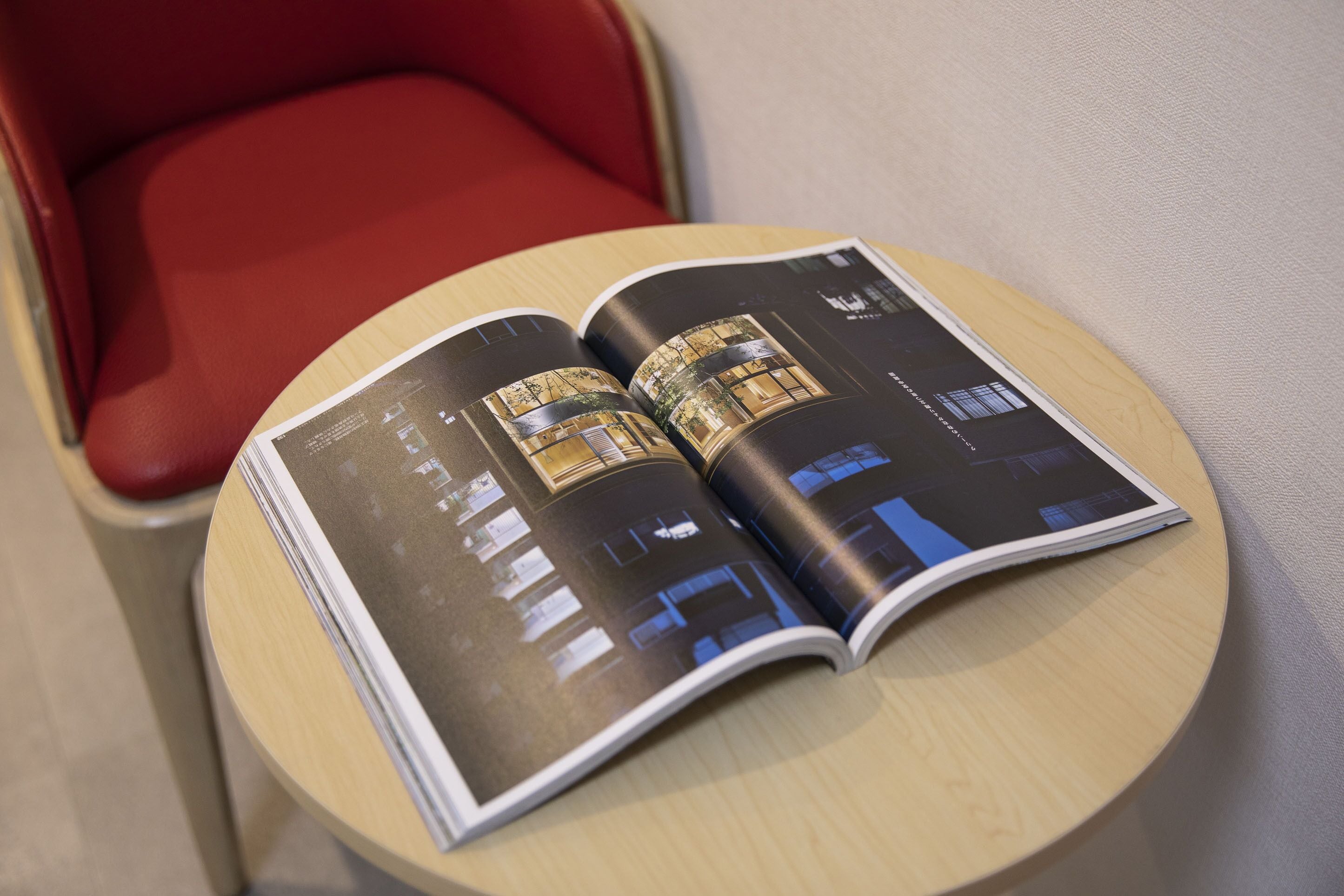 Un magazine est ouvert sur une table ronde, et l’on y voit l’intérieur d’un bâtiment, avec plusieurs pièces et un escalier.