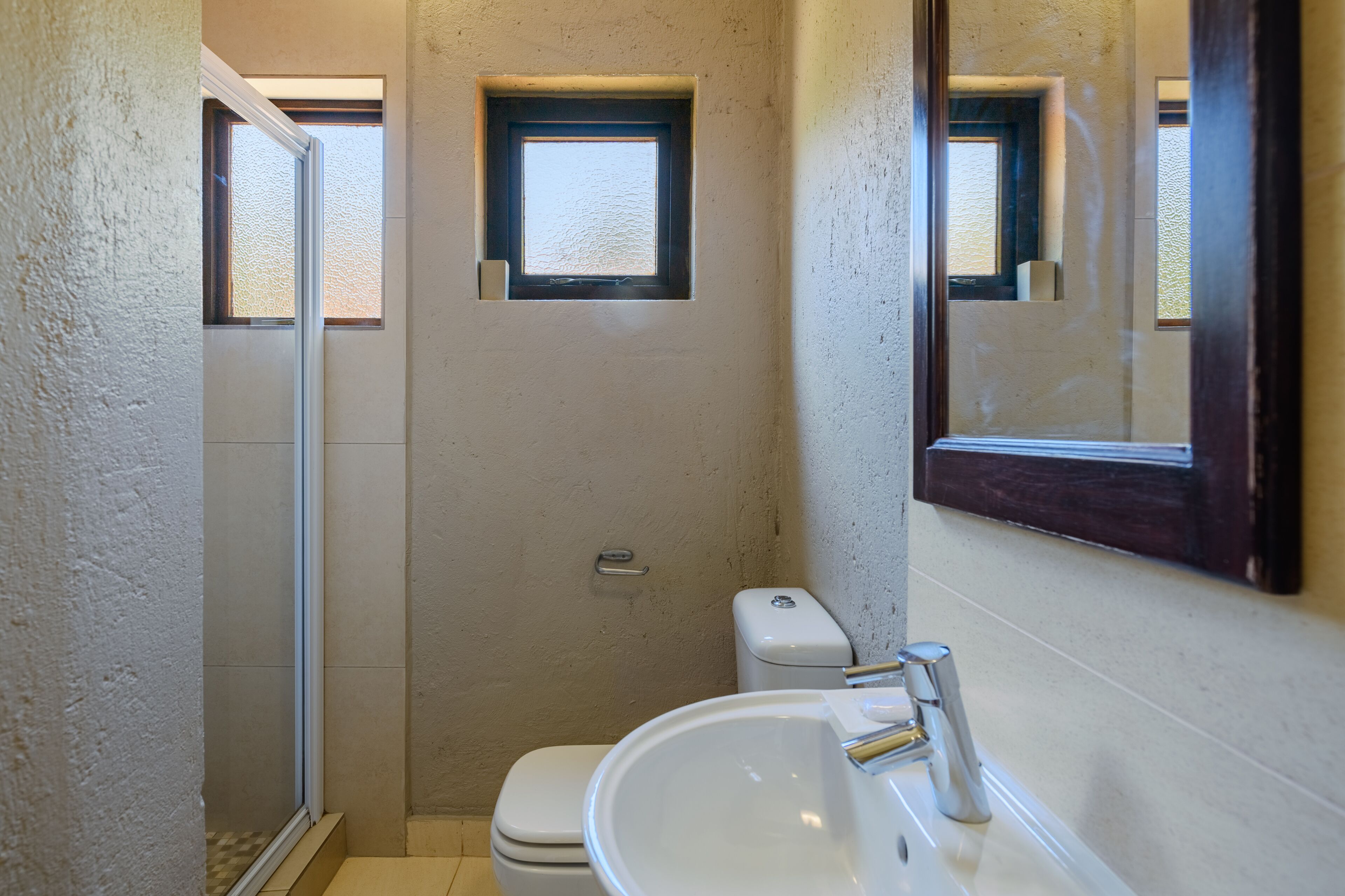 A small, compact bathroom with a toilet, sink, and a shower stall.