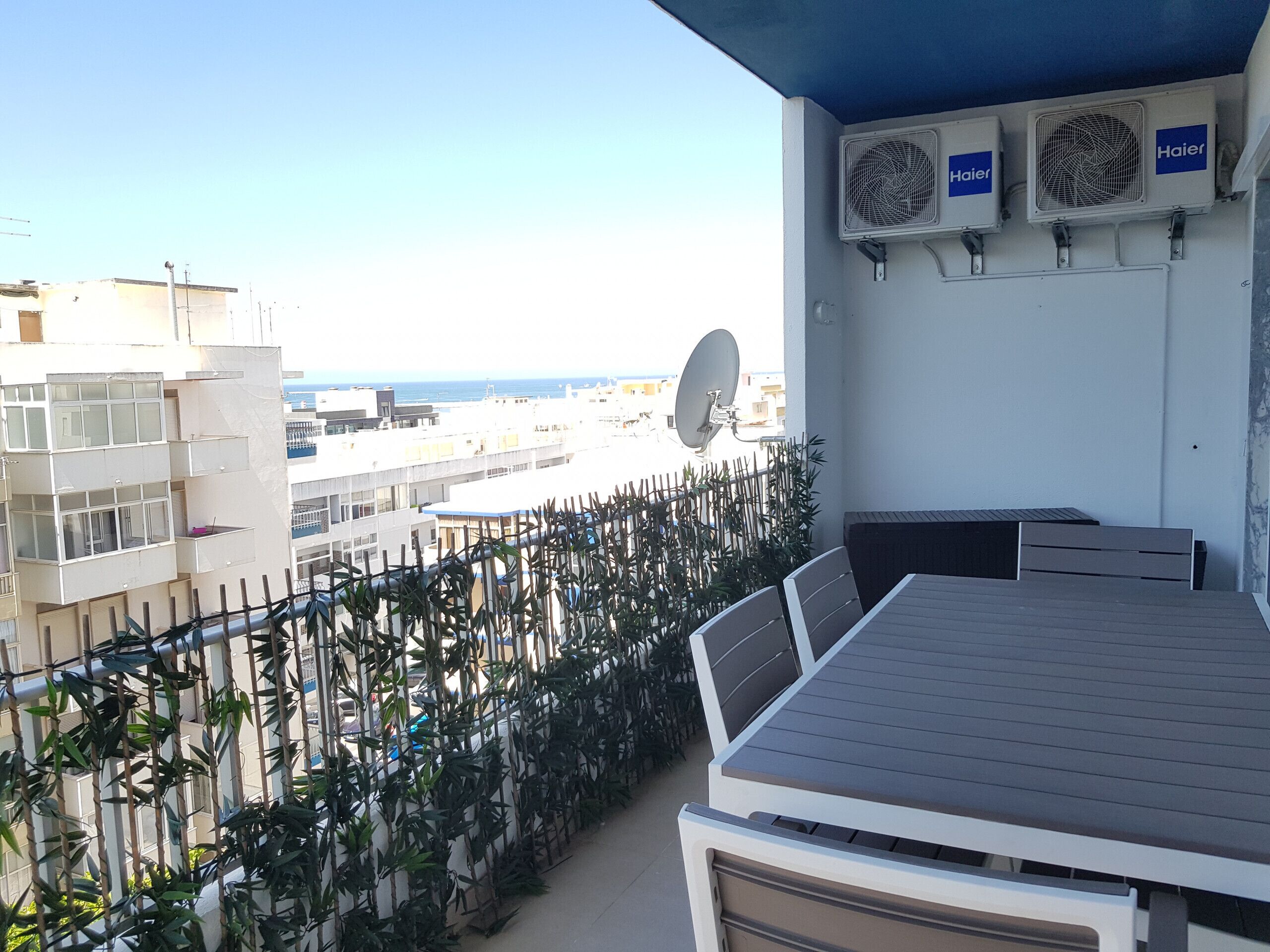 Ein Balkon mit Blick auf die Stadt, ein Tisch, Stühle und zwei Klimaanlagen.