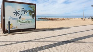 A beachside sign with palm trees and a beach view. - Alto Forte Novo 4, Vista Mar, Ar Condicionado e Garagem (Quarteira)