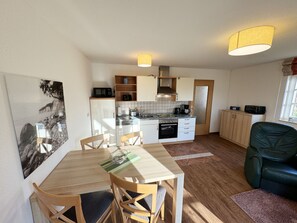 A compact kitchen with a dining area, a refrigerator, microwave, and a stove.