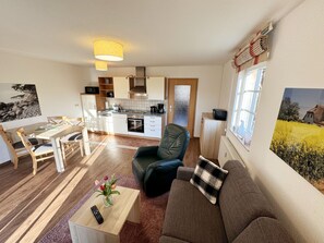 A compact living space with a dining area, kitchenette, and a sofa with a view of a field.