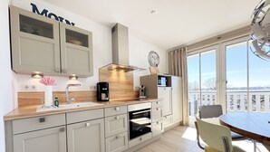Eine moderne Küche mit Holztischplatte, eingebauten Schränken, einer Kaffeemaschine und Blick auf die Stadt durch große Fenster.