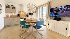 Eine moderne Küche mit Essbereich, einem Fernseher und einem großen Fenster.