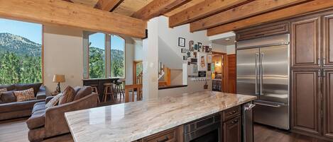 A modern kitchen with a large island, stainless steel appliances, and a view of the outdoors.