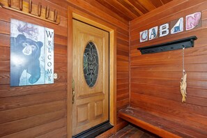 A wooden cabin interior with a wooden door, a welcome sign, and a cabin sign on the wall. - Breathtaking Ski Slope Views in Upper Moonridge! HOT TUB! Pet friendly! Arcade Games! Foosball! (Big Bear Lake)