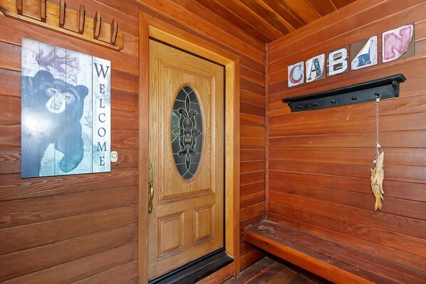 Ein Holzblockhaus-Innenraum mit Holztür, einer Willkommensschild und einem Hinweisschild an der Wand.
