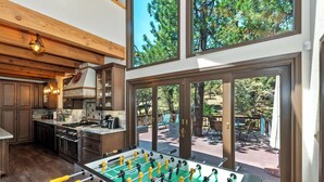 Una cocina amplia con armarios de madera, un ventanal grande y una mesa de futbolín.