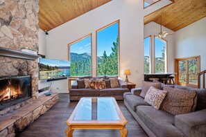 Una sala de estar acogedora con chimenea de piedra, ventanas amplias, un sofá y una mesa de centro.