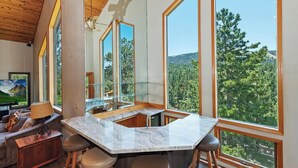 Una cocina moderna con ventanas amplias, encimera de mármol y zona de comedor con taburetes.