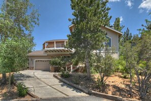 A two-story house with a covered porch and a garage. - Breathtaking Ski Slope Views in Upper Moonridge! HOT TUB! Pet friendly! Arcade Games! Foosball! (Big Bear Lake)