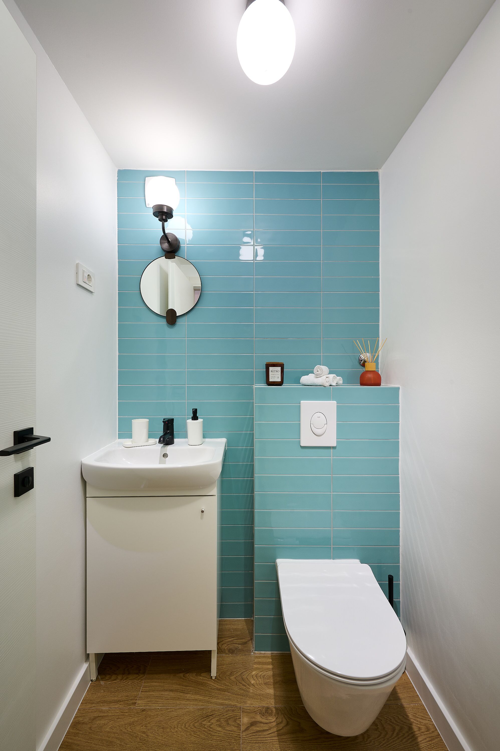 A small bathroom with a white sink, a toilet, and a blue tiled wall.